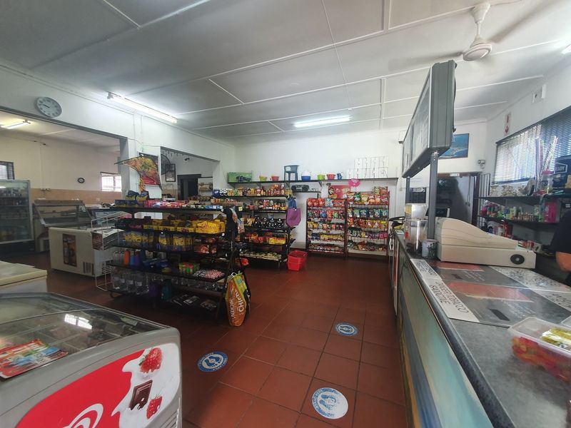 Interior view of a commercial retail space featuring tiled flooring, a service counter, and functional overhead lighting.