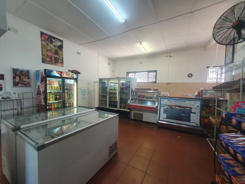 Commercial retail space featuring tiled flooring, functional fluorescent lighting, and multiple built-in commercial refrigeration units for product display.