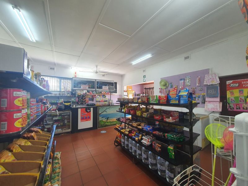A commercial retail space featuring tiled flooring, a service counter, and functional overhead lighting, suitable for a convenience store or small retail business.