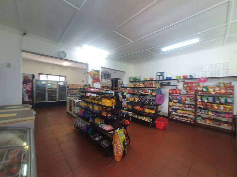 Interior view of a commercial retail space featuring tiled flooring, fluorescent lighting, and open shelving units for product display.