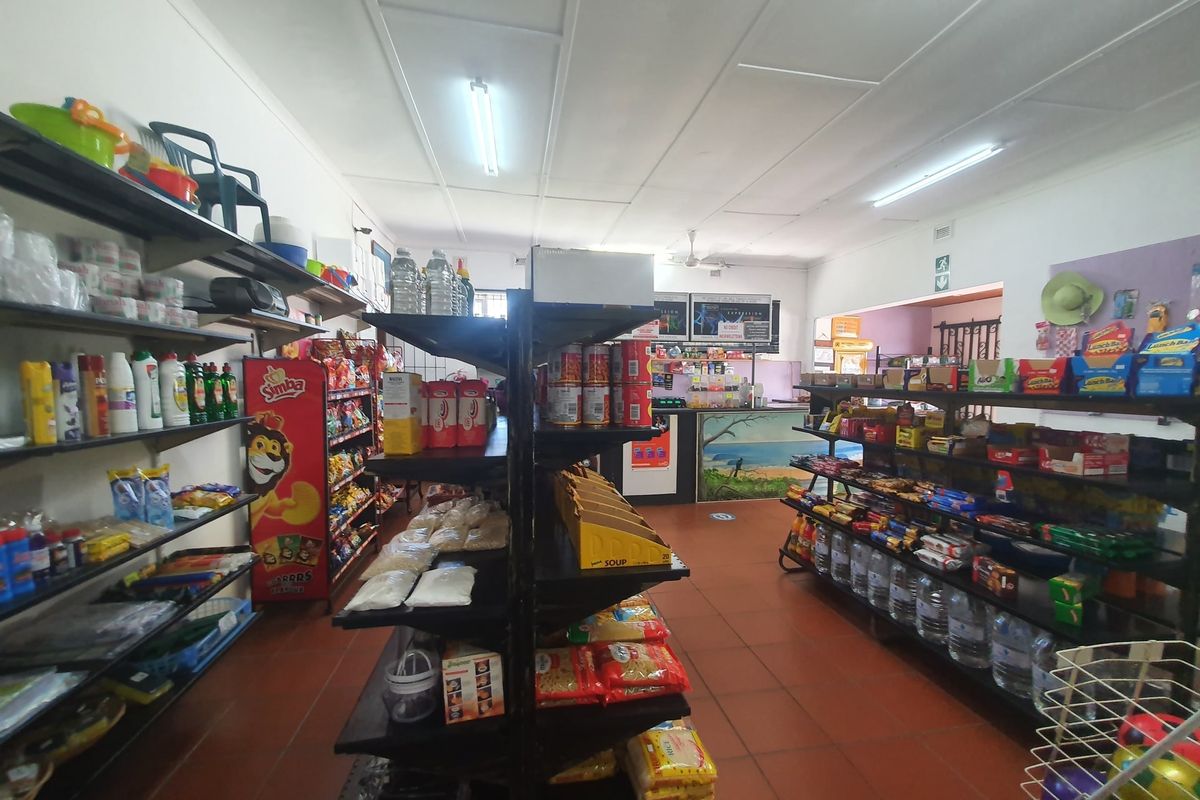 A commercial retail space featuring tiled flooring, fluorescent lighting, and a service counter, currently set up as a convenience store.