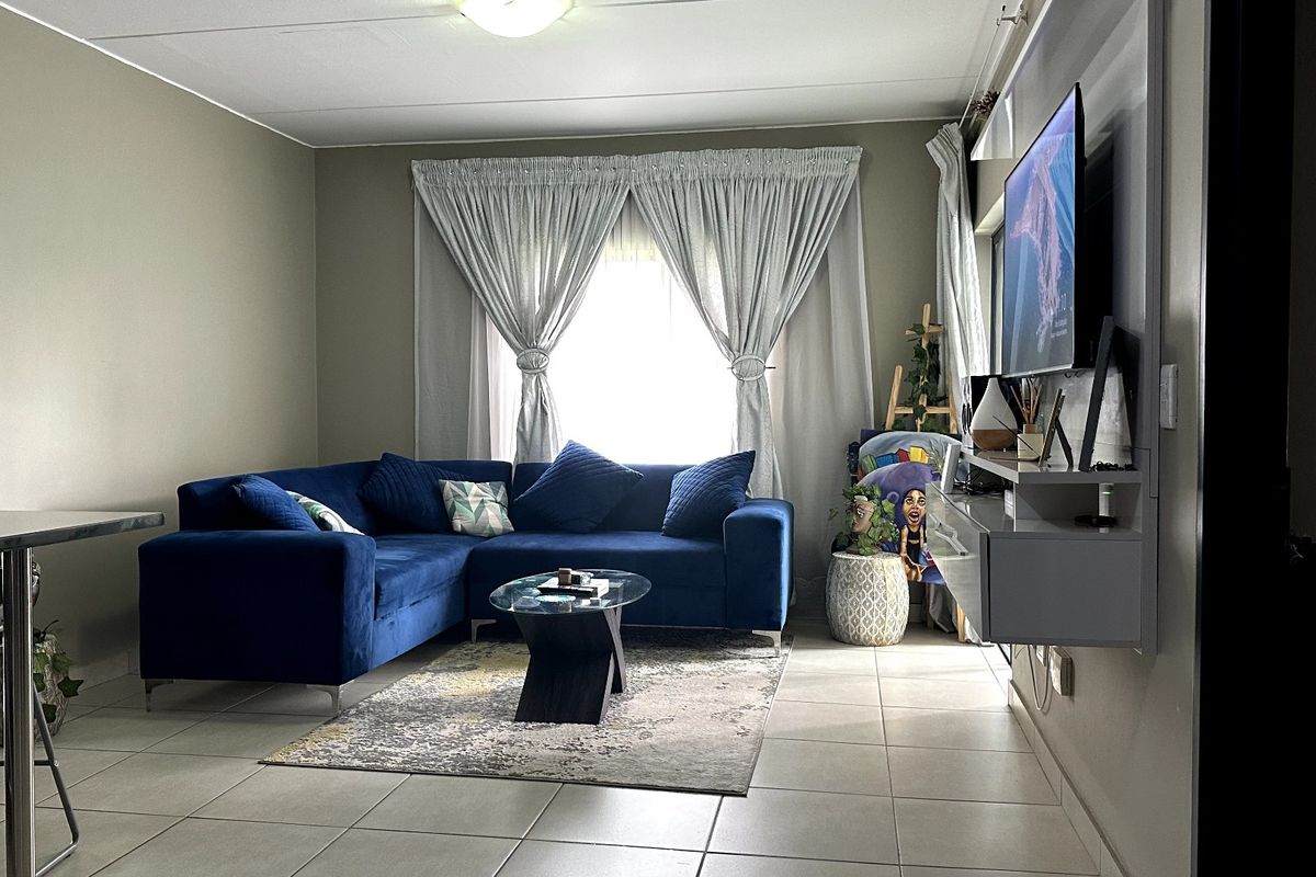 A comfortable living room featuring tiled flooring and a modern wall-mounted media console, creating a functional and inviting space.