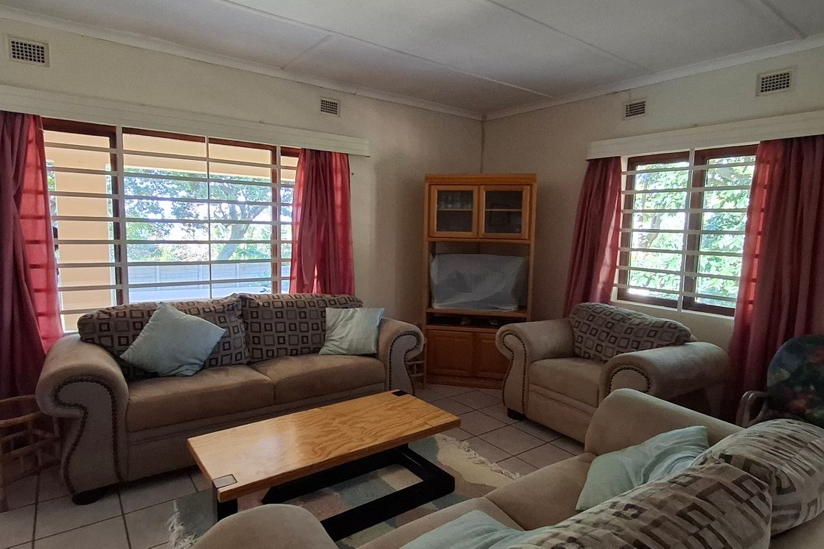 A living room featuring tiled flooring, large windows with security bars, and neutral wall finishes, offering a functional and well-lit space.