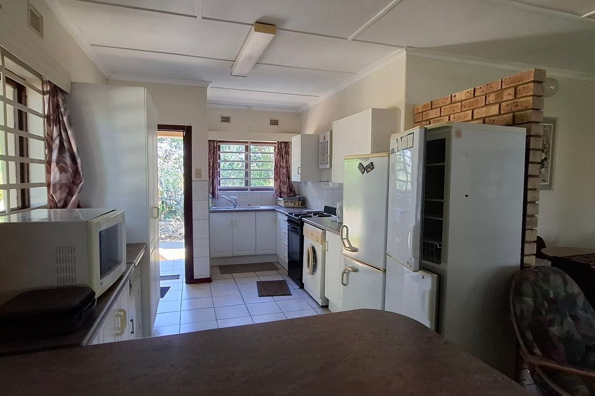 A functional kitchen featuring tiled flooring, built-in cabinetry, and an exposed brick partition, offering potential for modernization and layout optimization.