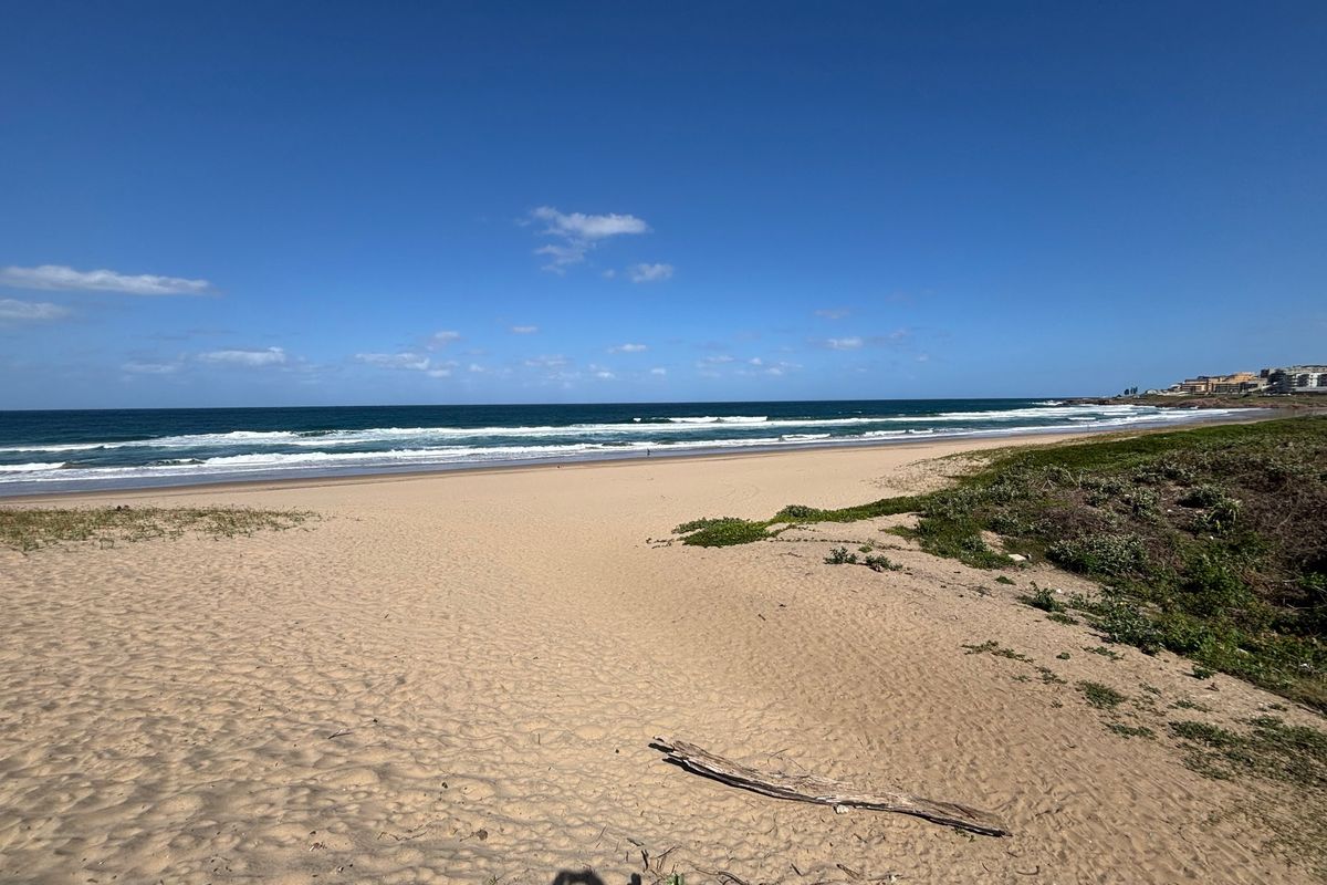 A scenic view of the sandy beach and ocean coastline, showcasing the natural surroundings of the property location.