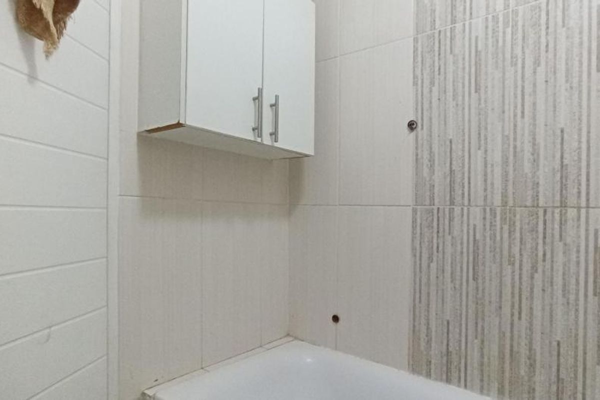 A bathroom featuring a bathtub and wall-mounted storage cabinet, currently showing signs of incomplete finishes and exposed wall fixtures.