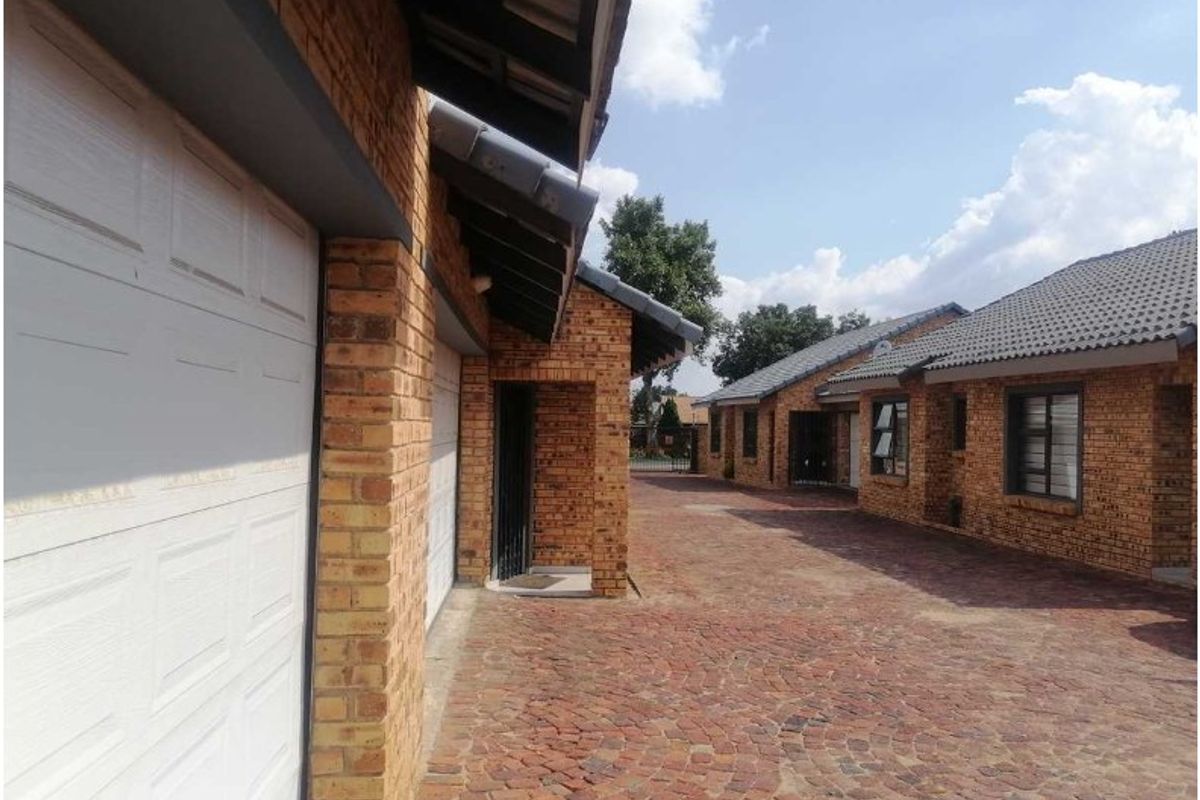 A view of the townhouse exterior featuring face brick construction, a paved driveway, and double garage access.