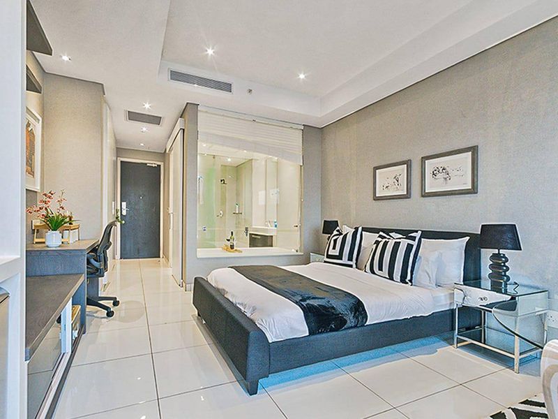 Modern bedroom featuring tiled flooring, recessed lighting, ducted air conditioning, and a unique glass-enclosed ensuite bathroom design.