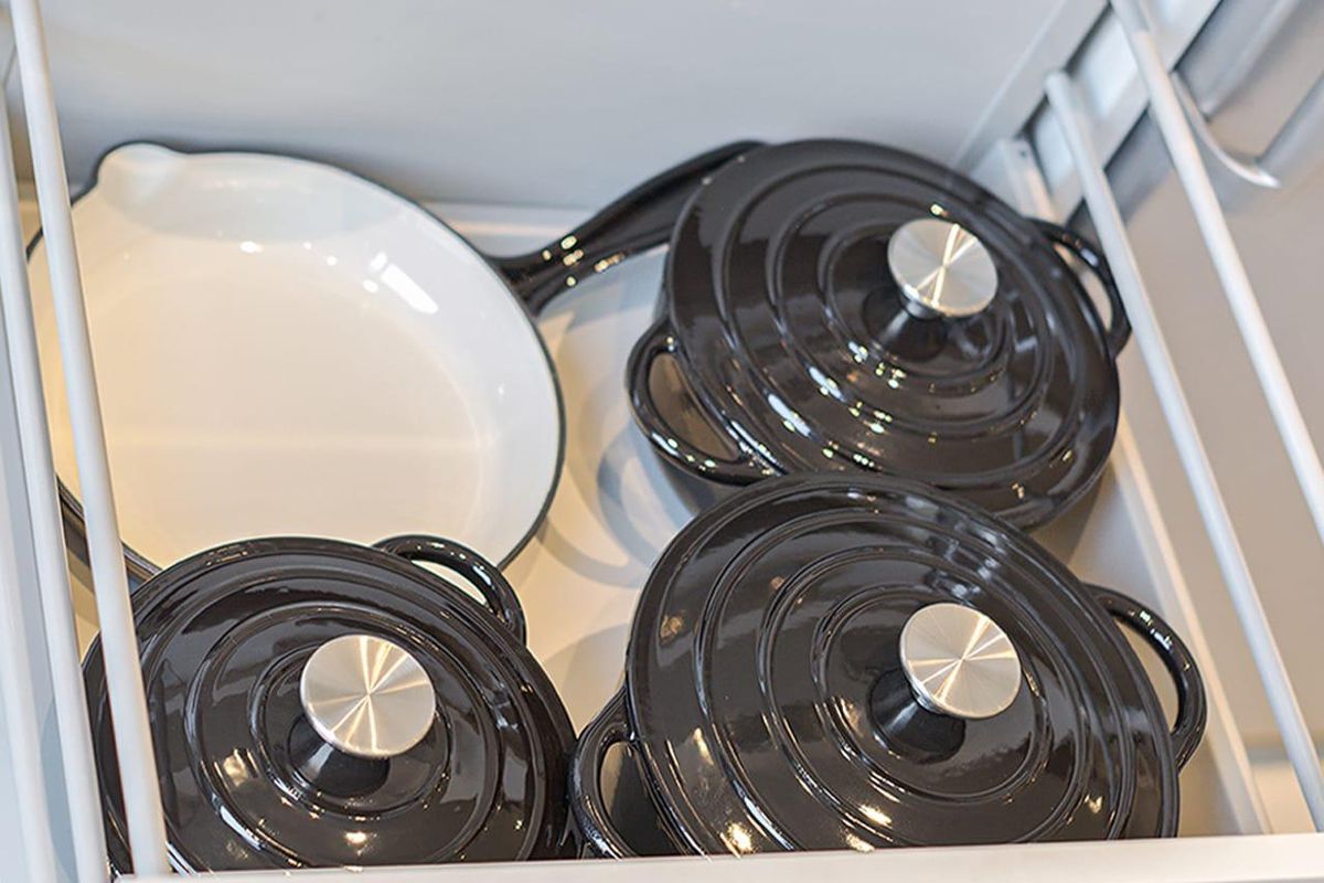 A close-up view of a clean, organized kitchen drawer containing high-quality cookware.
