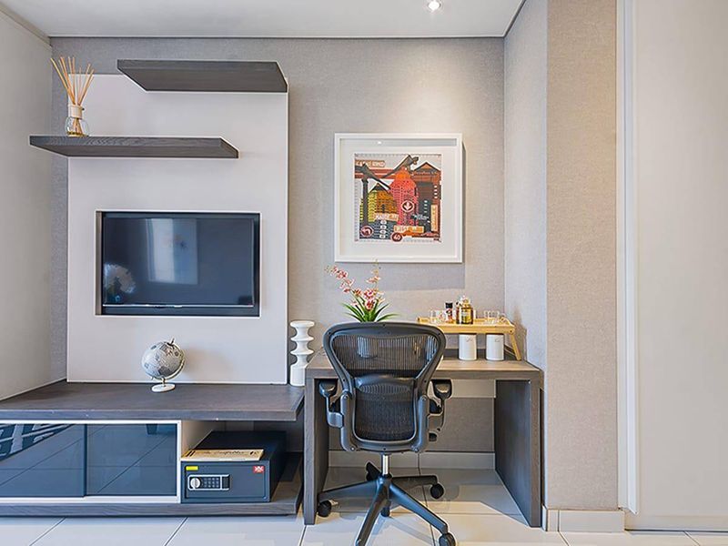 A modern, well-maintained home office area featuring built-in cabinetry, recessed shelving, and sleek tiled flooring.