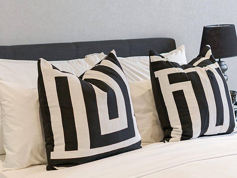 A close-up view of a bedroom setting featuring a neutral wall finish and a modern headboard.