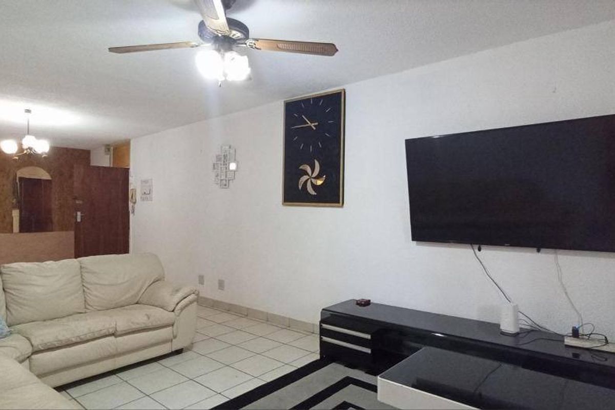 Spacious living area featuring tiled flooring and a ceiling fan, providing a functional and open layout for relaxation.