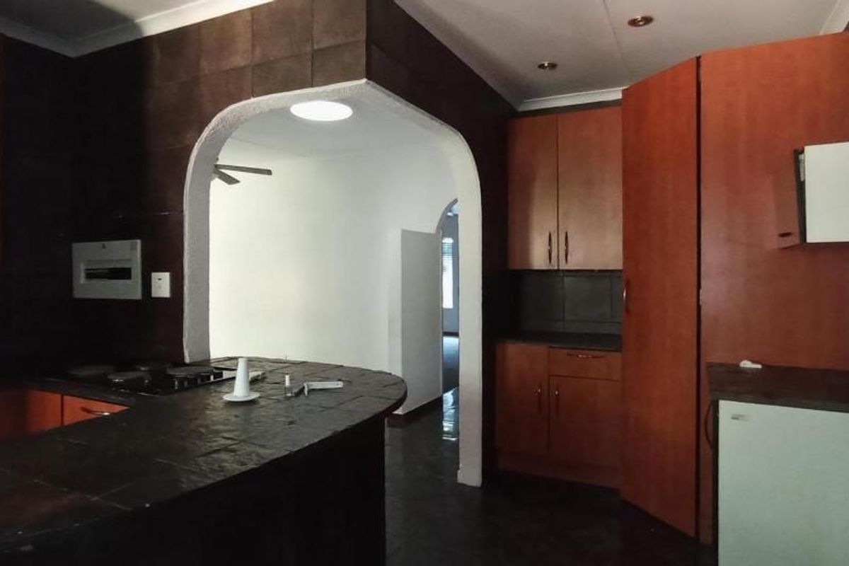 A functional kitchen featuring dark tiled countertops, built-in cabinetry, and an integrated oven, connected to the living area via a classic archway.