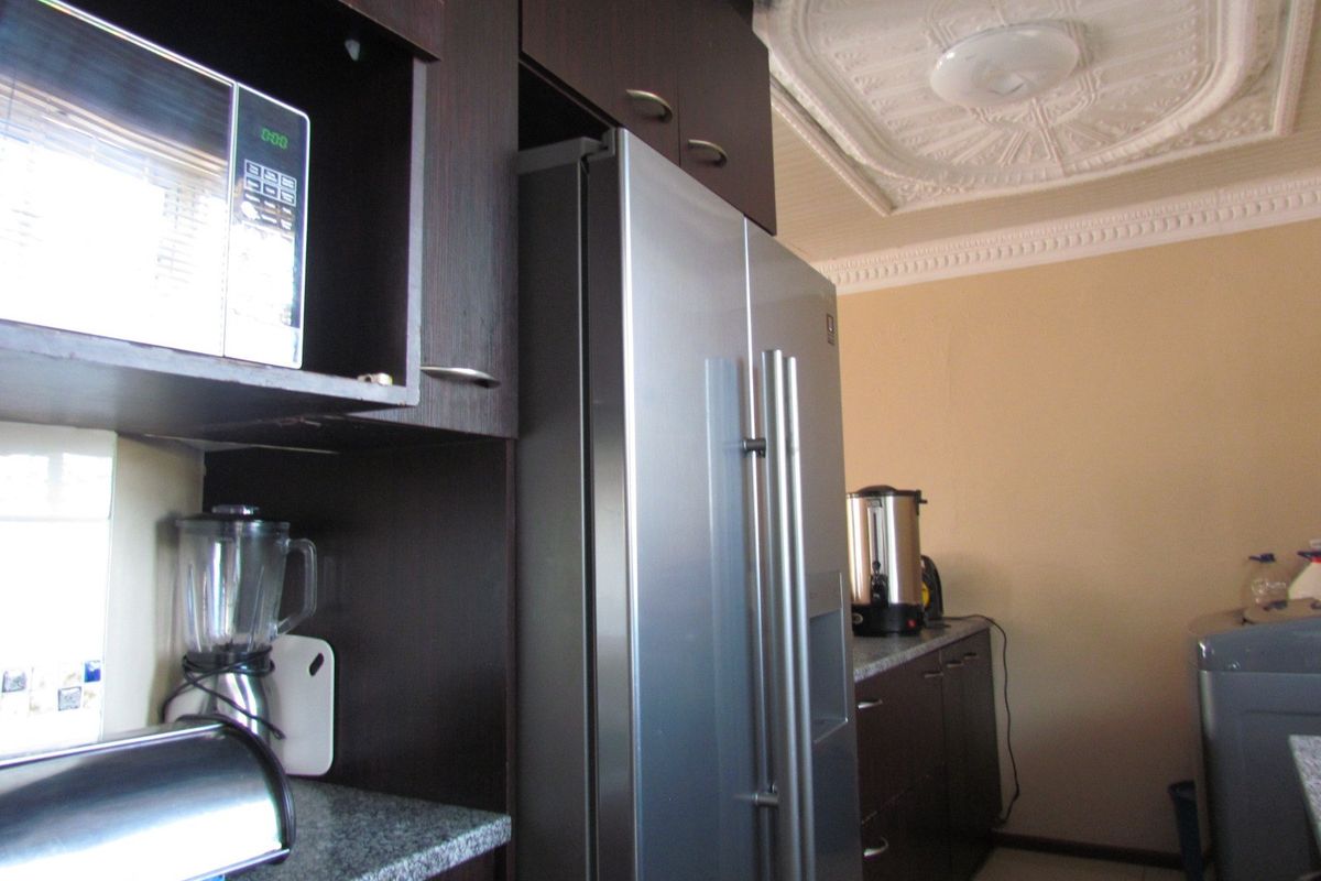 Kitchen area featuring dark wood cabinetry, granite countertops, a built-in microwave, and decorative ceiling detailing.