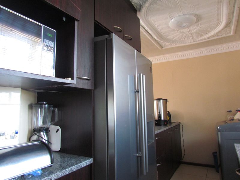 Kitchen area featuring dark wood cabinetry, granite countertops, a built-in microwave, and decorative ceiling detailing.