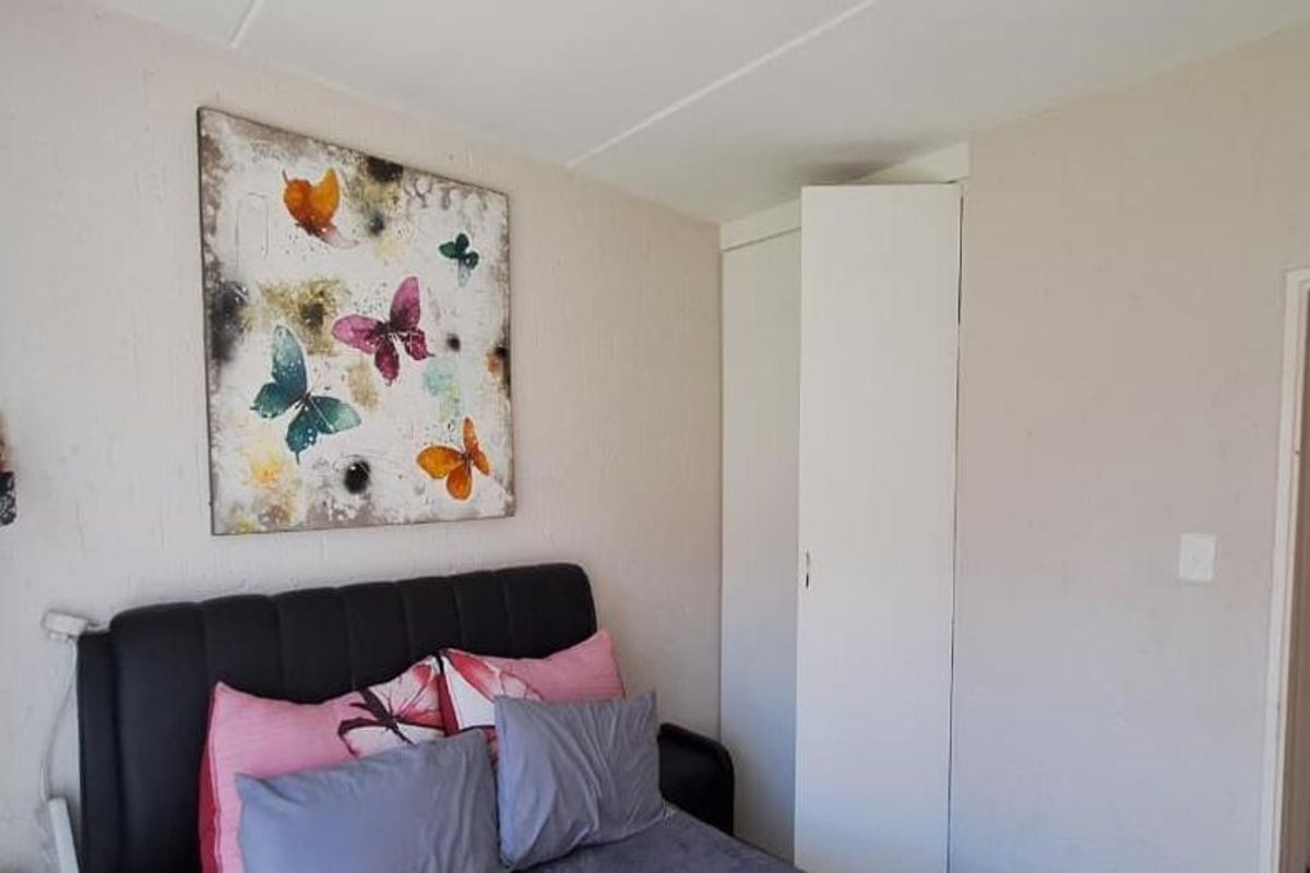 A bedroom featuring a built-in cupboard and textured wall finishes.
