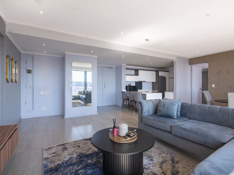 Modern open-plan living area featuring tiled floors, recessed lighting, and a sleek kitchen with built-in cabinetry and a central island.