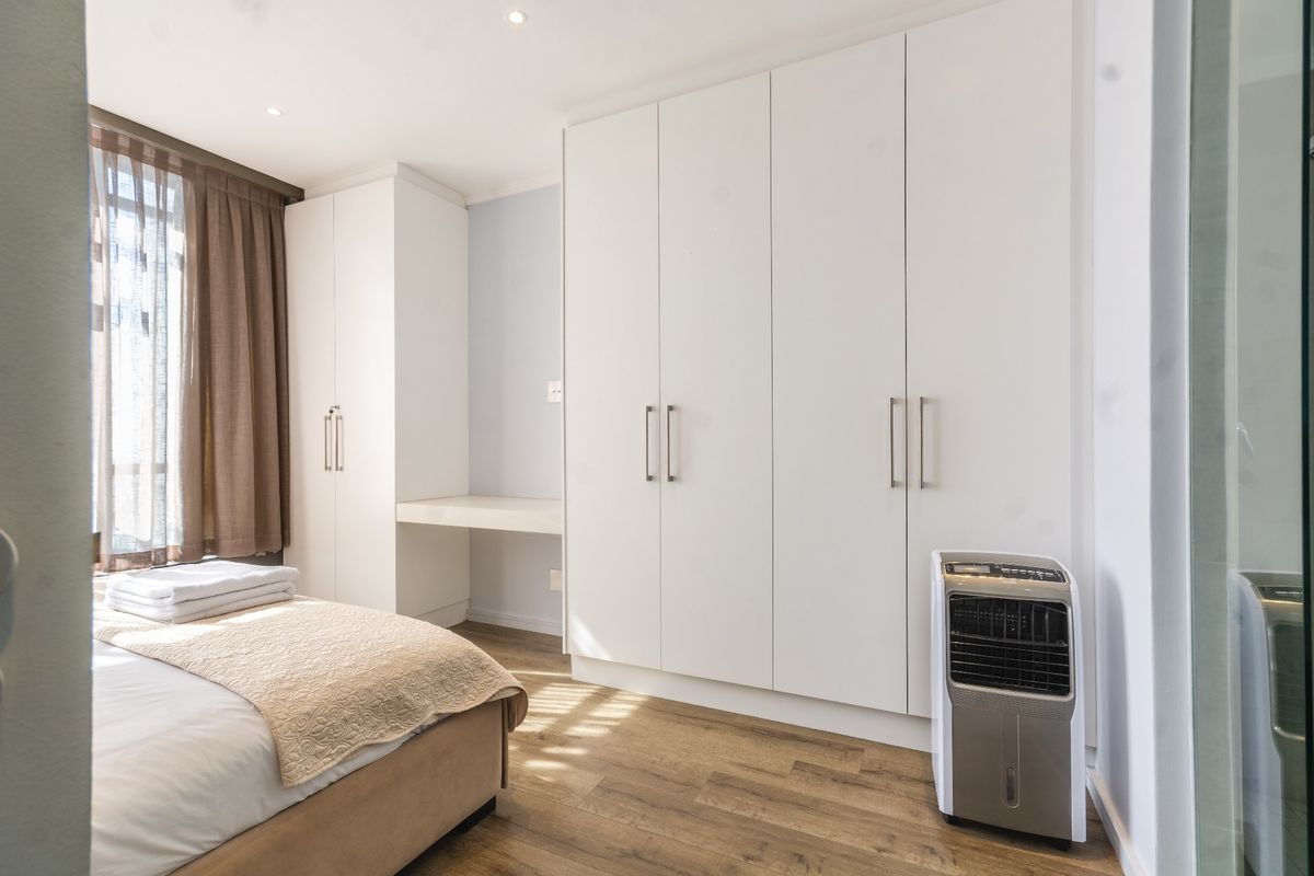 A well-maintained bedroom featuring extensive built-in cabinetry, a integrated desk area, recessed lighting, and modern laminate flooring.