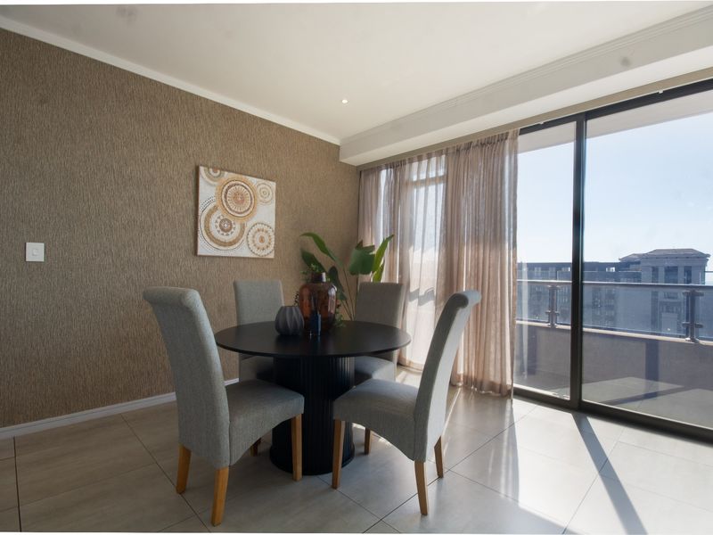 A bright dining area featuring textured wallpaper, large sliding glass doors leading to a balcony, and modern floor tiles.