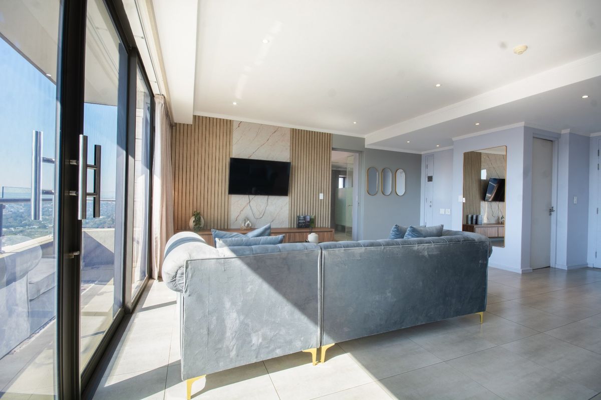 Modern living room featuring large sliding glass doors, tiled flooring, and a stylish feature wall with wood slats and marble accents.