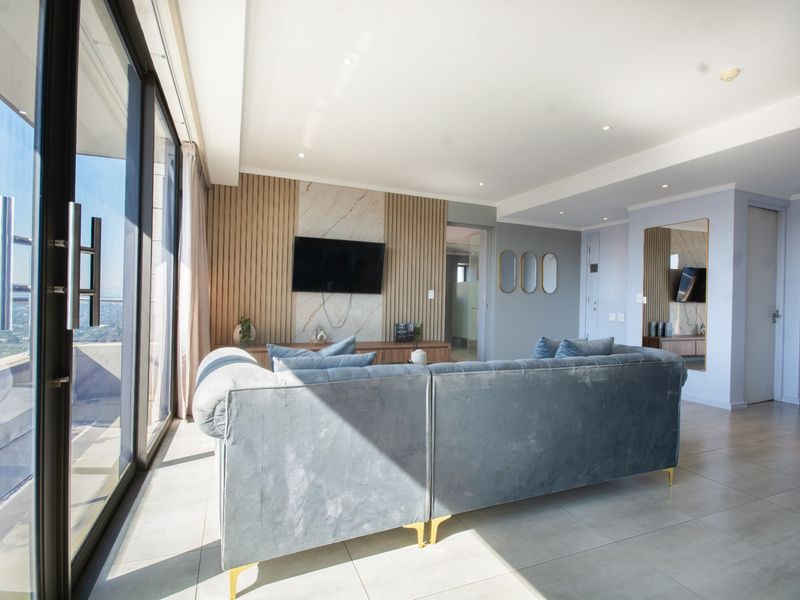 Modern living room featuring large sliding glass doors, tiled flooring, and a stylish feature wall with wood slats and marble accents.