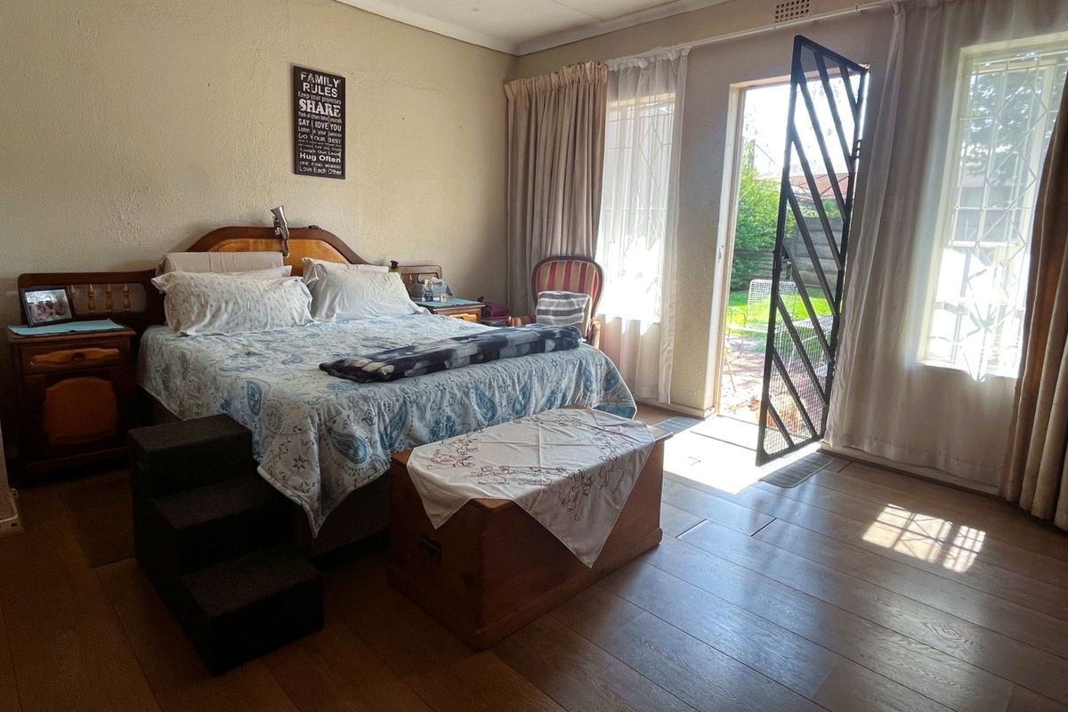 A bedroom featuring laminate flooring and direct access to the garden through a security gate.