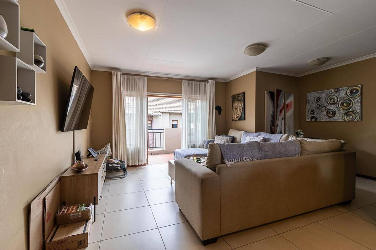 A comfortable living room featuring tiled flooring and a sliding glass door that provides access to an outdoor balcony area.
