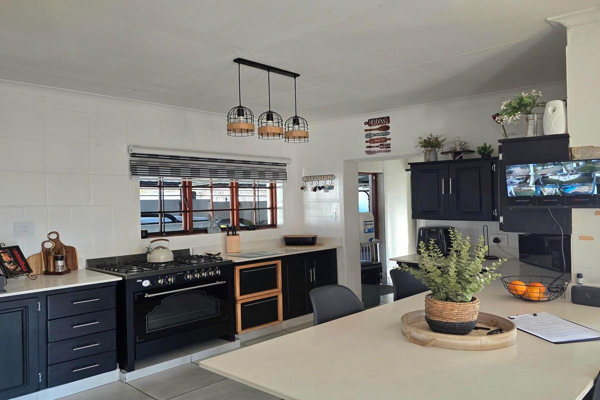 A well-maintained kitchen featuring dark cabinetry, stone countertops, a gas stove, and a central island, providing a functional and modern cooking space.