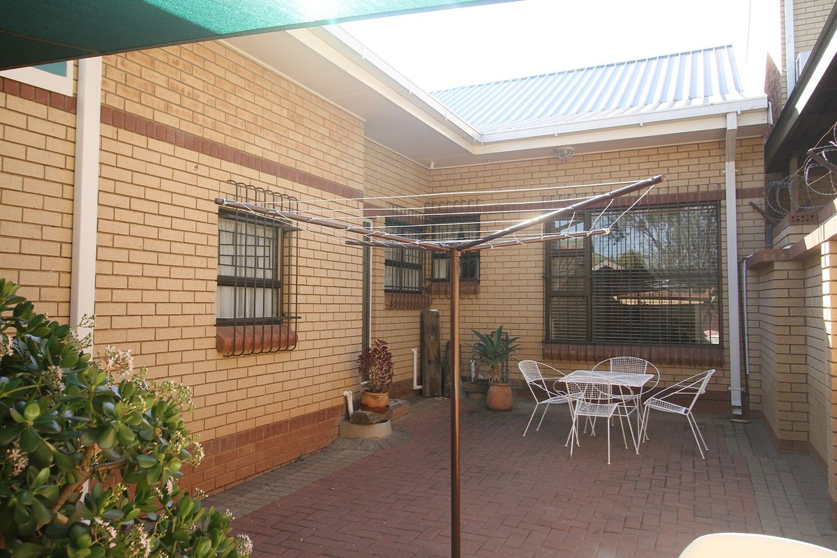 A paved rear courtyard featuring face brick walls, security-barred windows, and a rotary clothesline, providing a functional outdoor utility space.