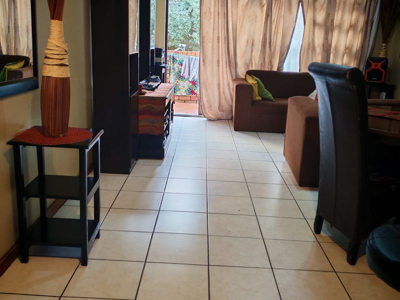 A living room area featuring ceramic floor tiles and a sliding glass door leading to an outdoor space.