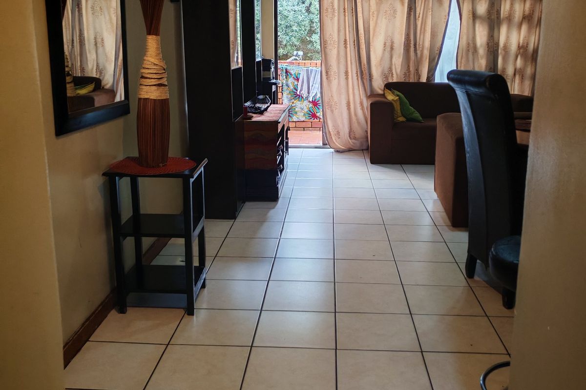 A living room area featuring tiled flooring and a sliding glass door leading to an outdoor space.
