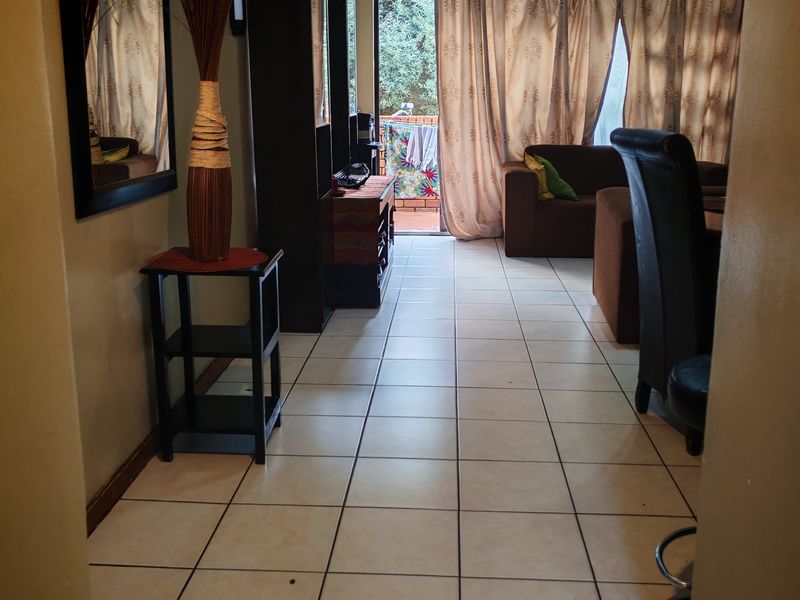 A living room area featuring tiled flooring and a sliding glass door leading to an outdoor space.
