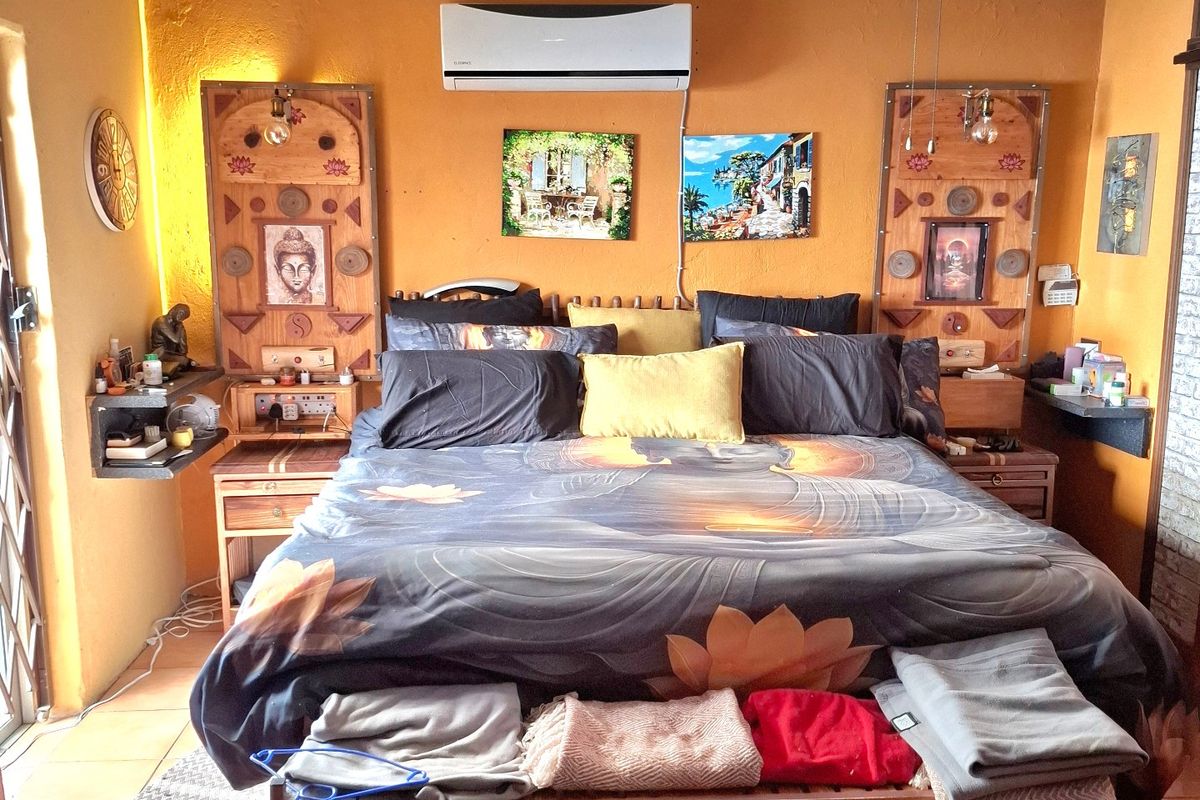 A bedroom featuring tiled flooring, a ceiling fan, and a wall-mounted split-system air conditioner.