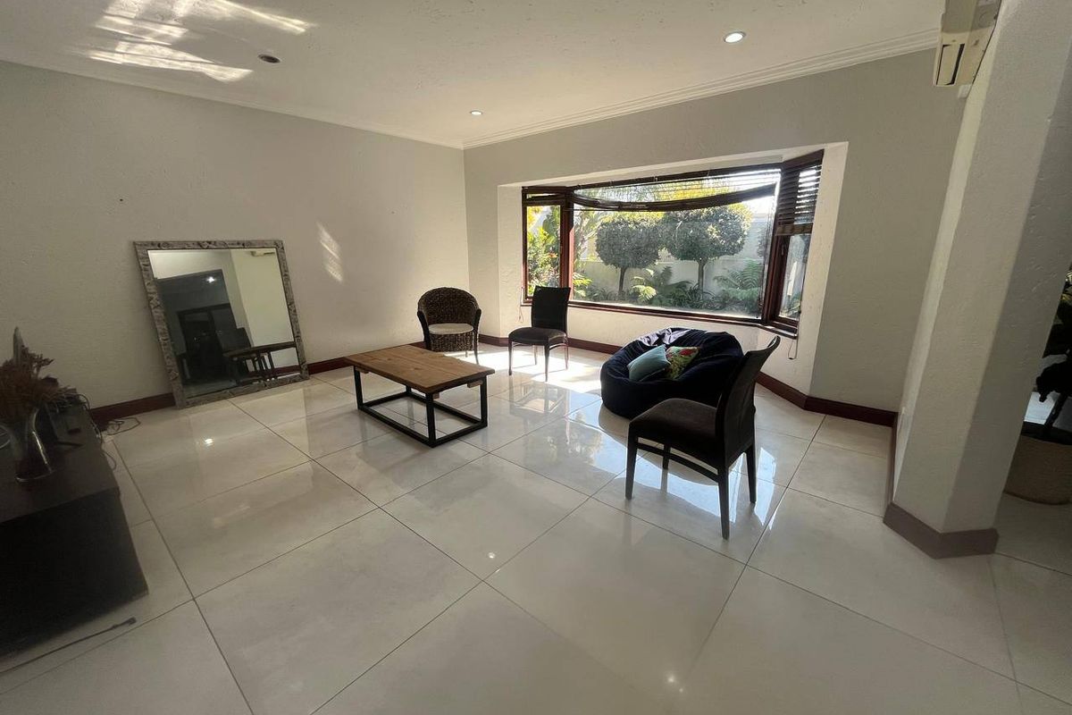 Spacious living room featuring large bay windows, polished porcelain floor tiles, and recessed downlighting, offering a bright and open atmosphere.