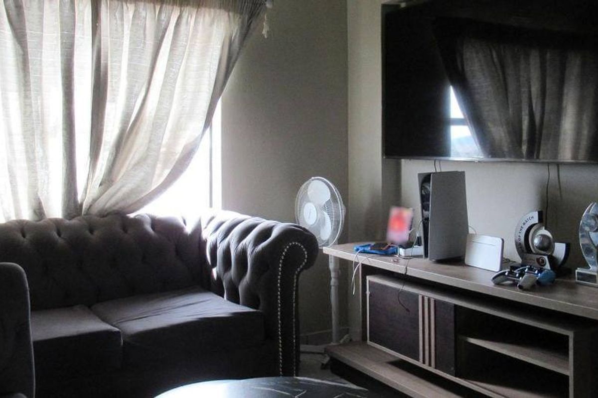 A cozy living room area featuring a wall-mounted television and neutral wall tones, providing a comfortable space for relaxation.