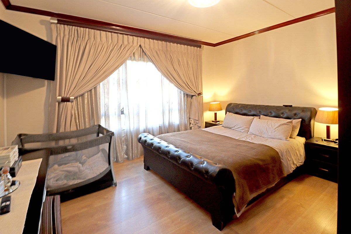 A well-proportioned bedroom featuring laminate flooring and crown molding, providing a comfortable and functional living space.