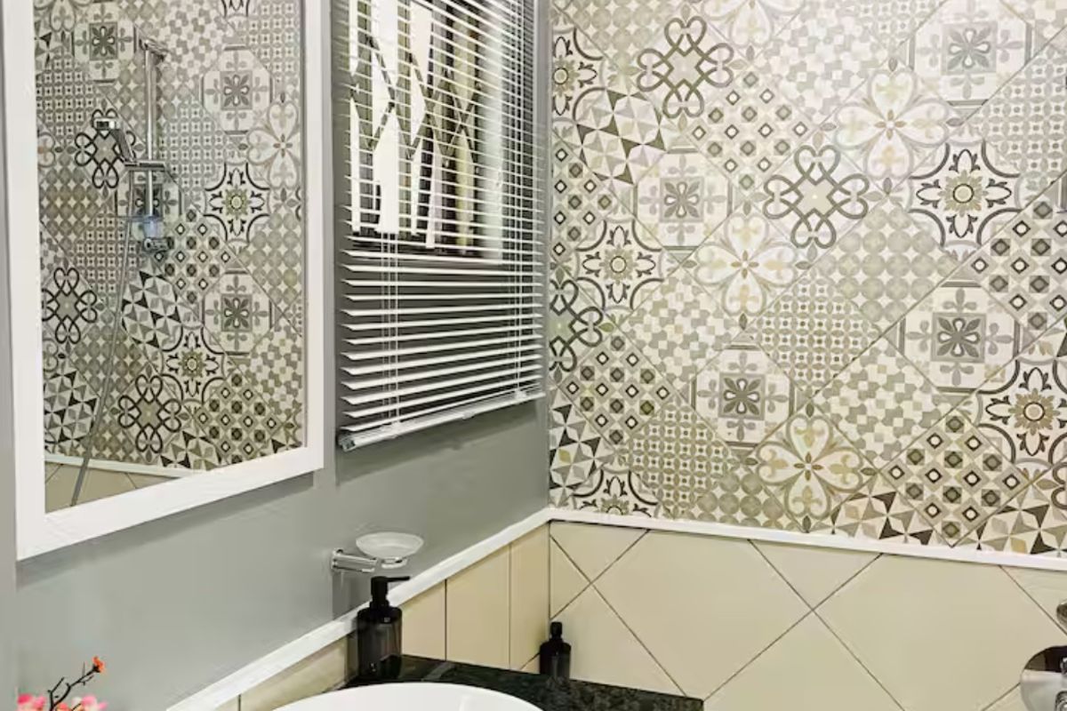 A well-maintained bathroom featuring a granite-topped vanity with a vessel sink, a bathtub, and decorative patterned wall tiling.