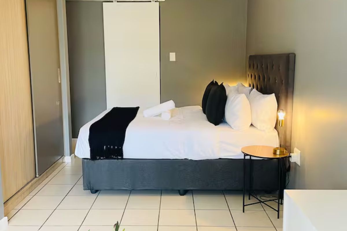 A well-maintained bedroom featuring tiled flooring, neutral wall tones, and a large built-in wardrobe with sliding doors.