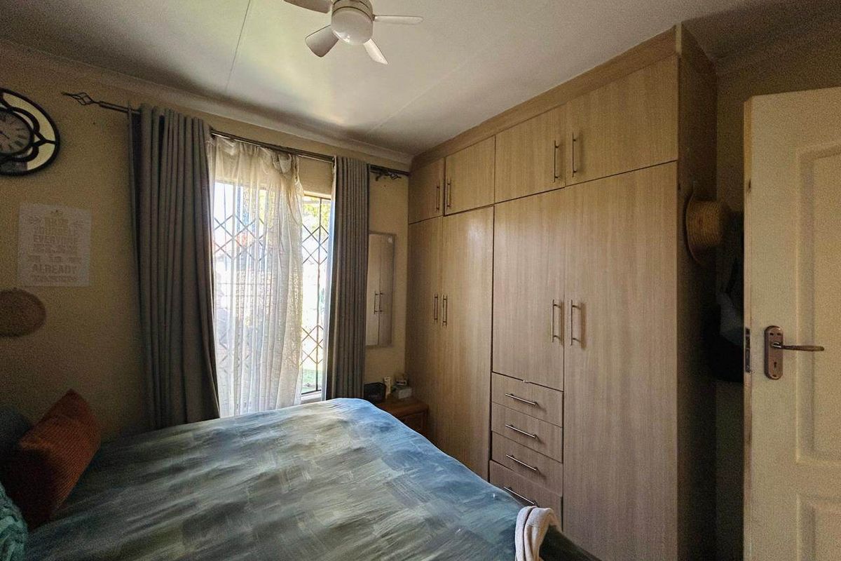 A functional bedroom featuring extensive built-in wooden cabinetry for storage and a ceiling fan for climate control.