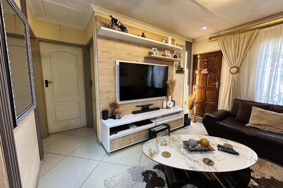 A cozy living room featuring a custom built-in media unit with timber paneling, tiled flooring, and recessed ceiling lighting.