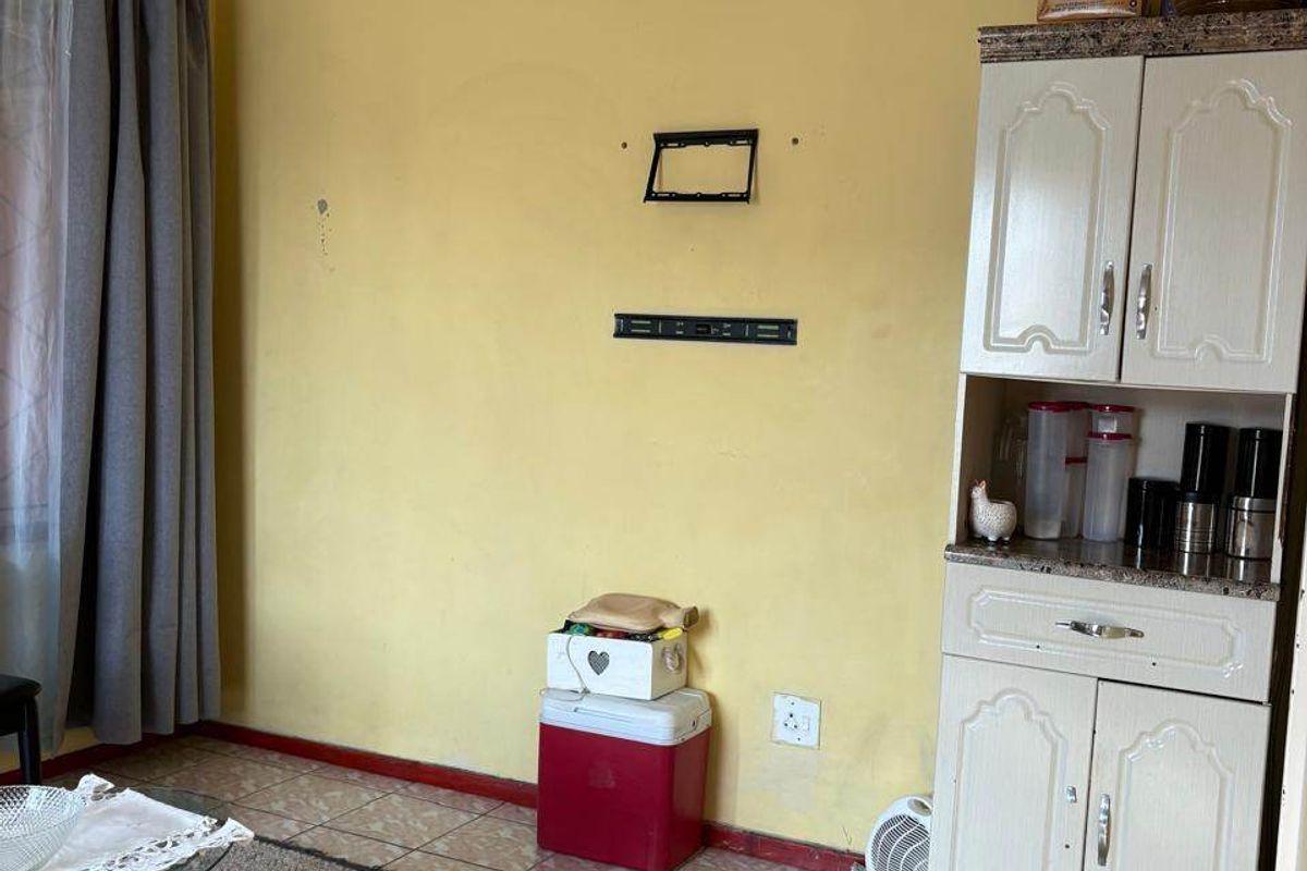 Living room featuring tiled flooring, decorative ceiling tiles, and a built-in storage cabinet. The space requires cosmetic updates to improve its overall condition.