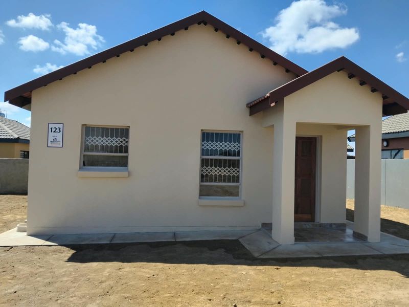 Front elevation of a modern single-story house featuring a tiled roof, covered entrance porch, and security bars on the windows.