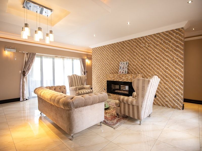 Spacious living room featuring polished tile flooring, a decorative feature wall with a built-in fireplace, and elegant recessed ceiling lighting.