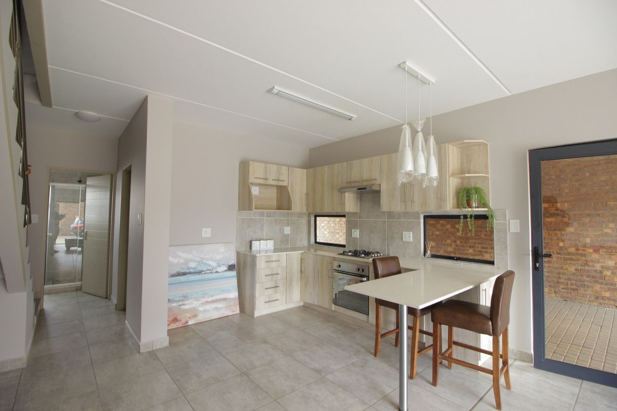 Modern kitchen featuring light wood cabinetry, built-in gas hob and oven, tiled backsplash, and an integrated breakfast counter with direct access to the exterior.