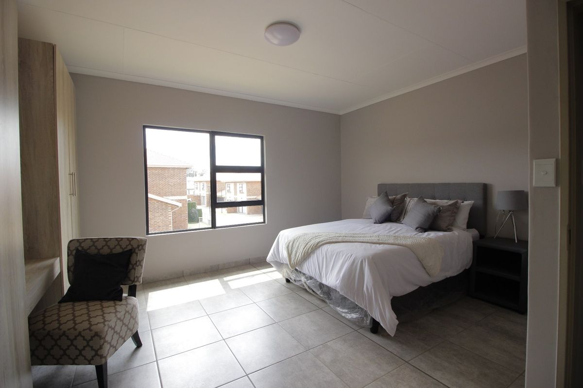 A well-maintained bedroom featuring neutral wall tones, tiled flooring, and a built-in wardrobe, offering a clean and functional living space.