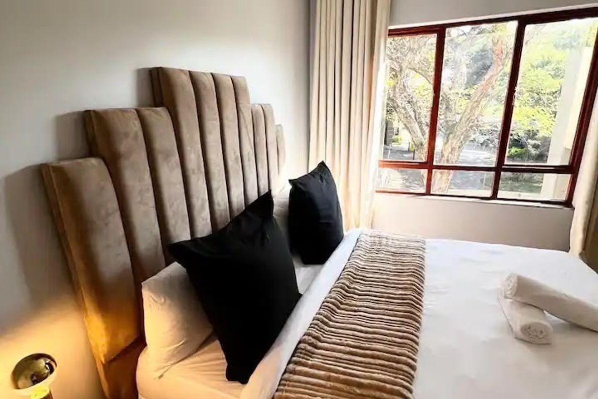 A well-lit bedroom featuring a large window with natural light and neutral wall finishes.