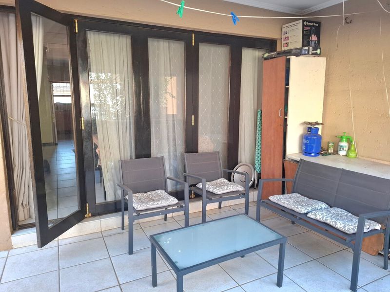 A covered patio area featuring tiled flooring and dark-framed bi-fold doors providing access to the interior living space.