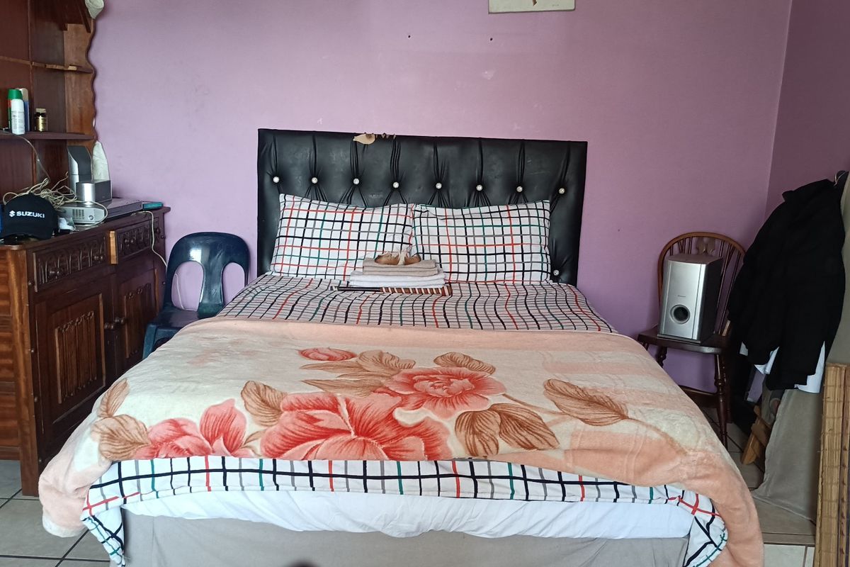 A bedroom featuring tiled flooring and a tufted headboard. The space would benefit from cosmetic updates to improve its overall appeal.