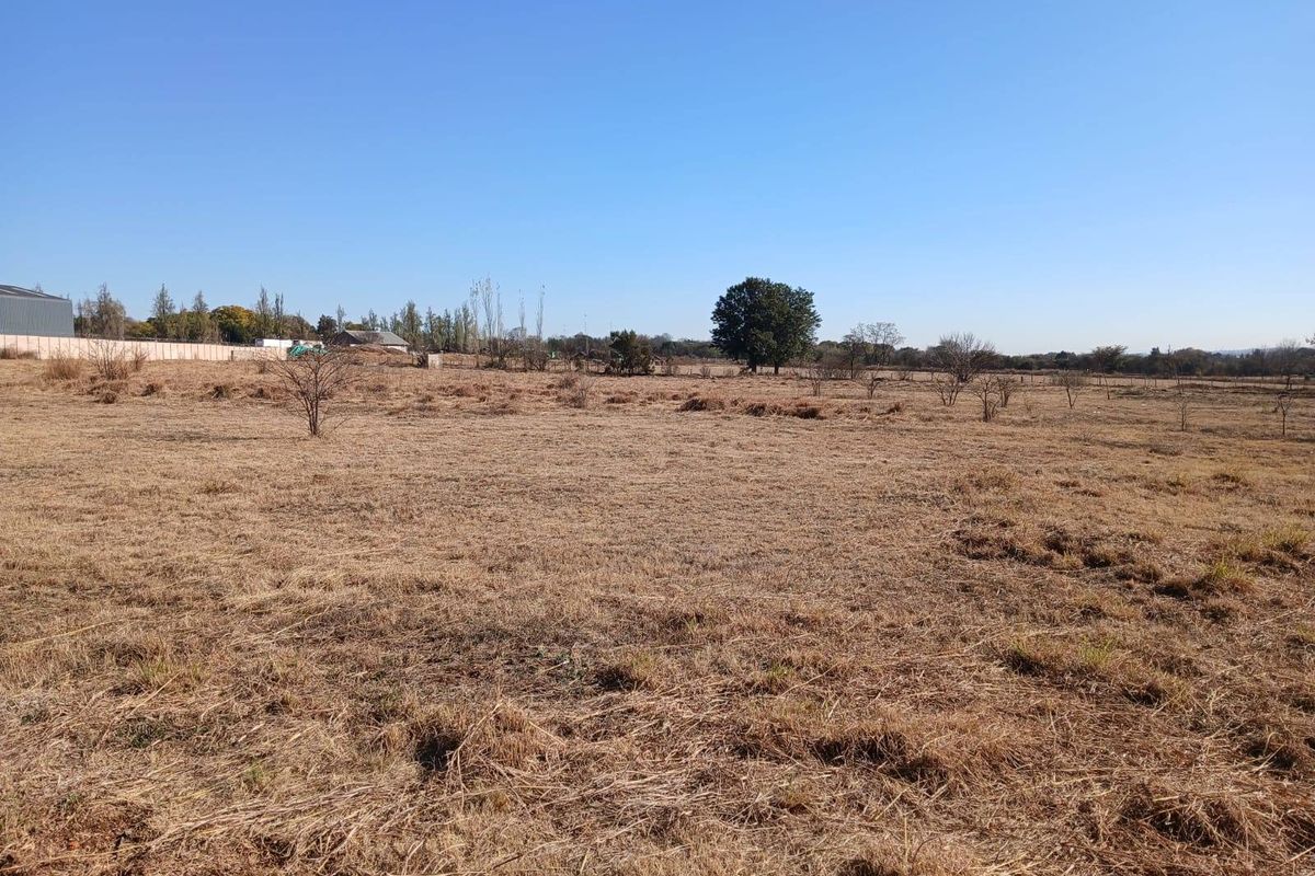 Expansive open farm land with dry grass, scattered trees, and perimeter fencing, offering significant potential for agricultural or development use.