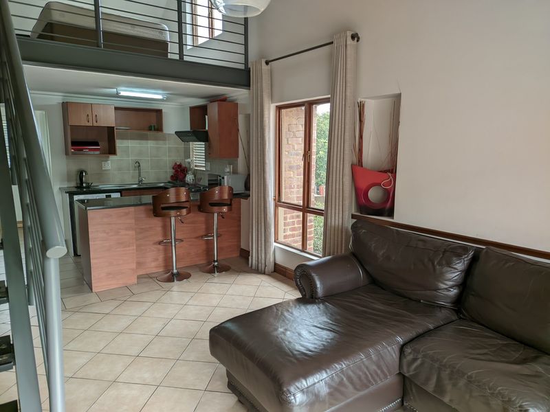 Open-plan living area featuring a kitchen with granite countertops, tiled flooring, and a mezzanine level accessed by a staircase.